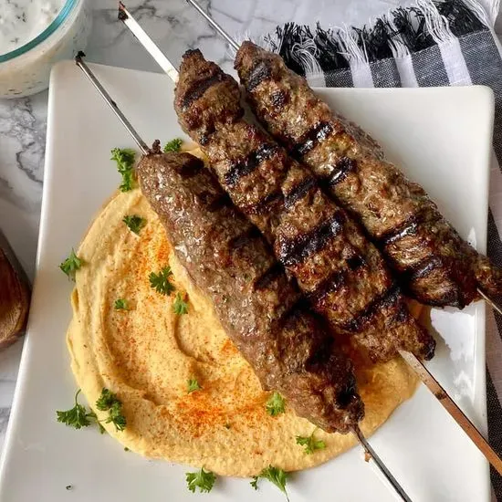 Beef Kabab Plate -  Grilled beef kabab marinated in Mediterranean spice with rice, served with  grilled tomato, grilled onion, hummus, nutty tahini, and a refreshing salad. 